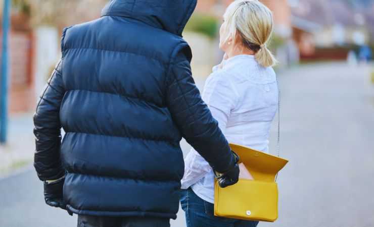 una ragazza al telefono e un uomo che le ruba dalla borsa