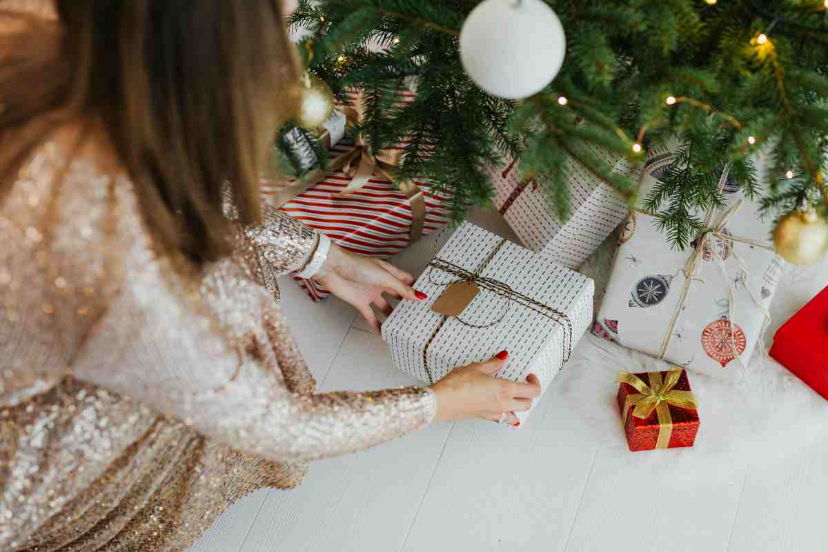 donna che mette i pacchi sotto l'albero di natale