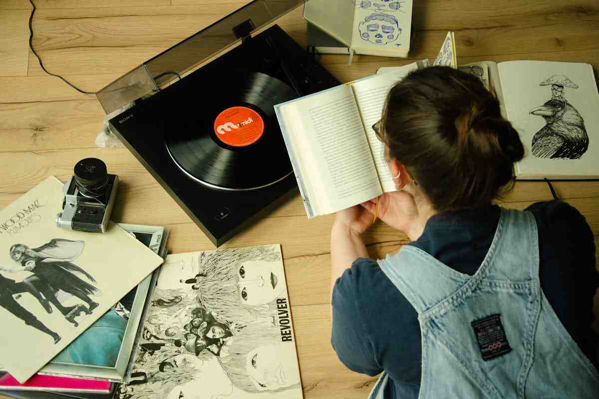 Persona che legge un quaderno e con un vinile vicino