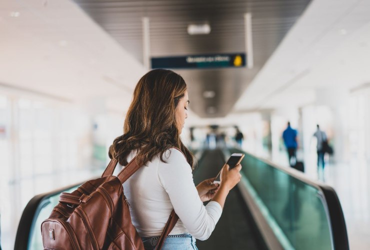 Ragazza con cellulare in mano in aeroporto