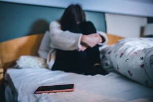 Ragazza triste sul letto con smartphone