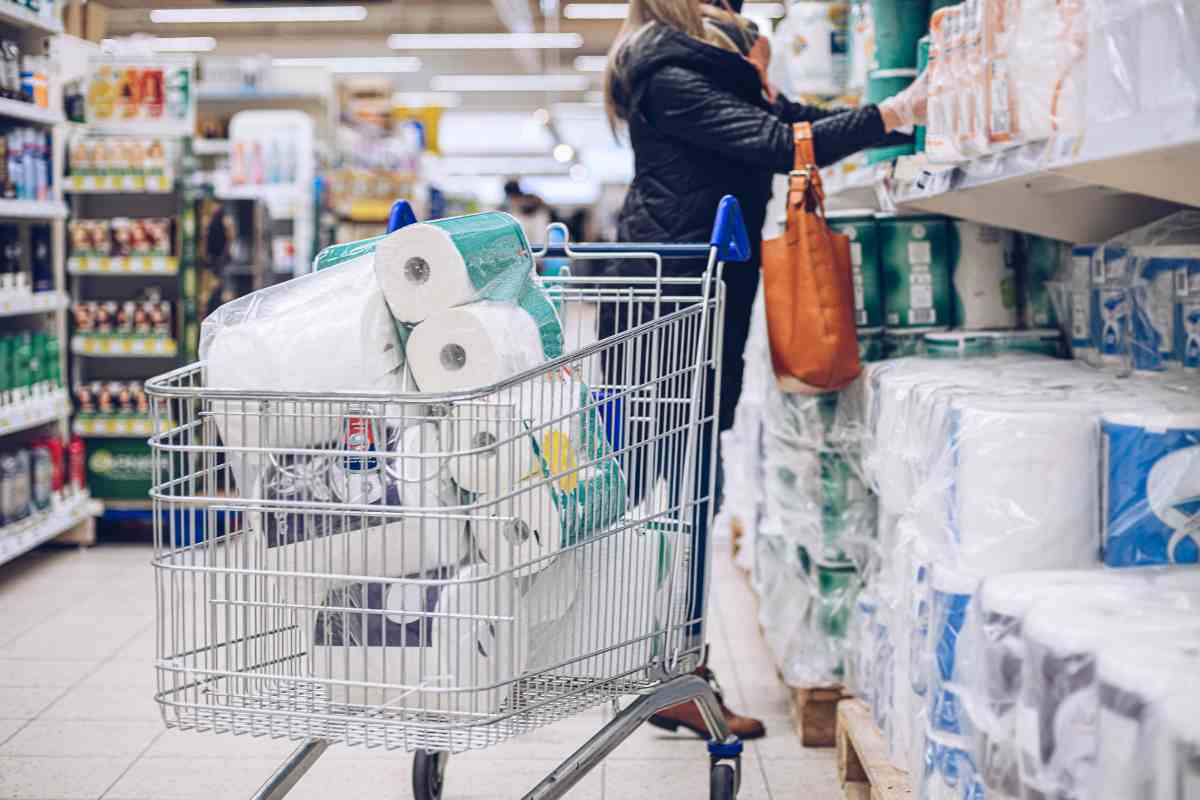 Donna che acquista carta igienica e carta da cucina supermercato